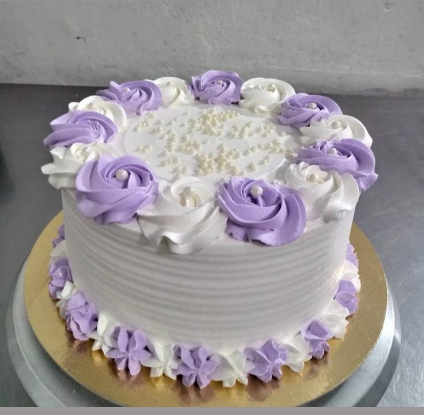 White cake with purple and white floral decorations on a gray surface